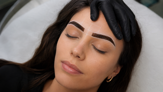 Henna brow treatment with white mapping lines and dark henna applied inside the brow shape