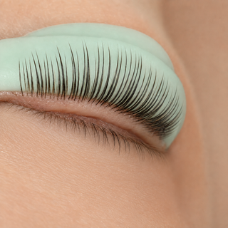 Natural lashes precisely placed on a single mint shield during a professional lash lift