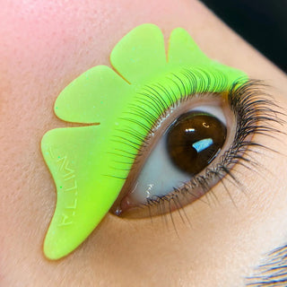 Green eyelash extension tool on an eye with a blurred background