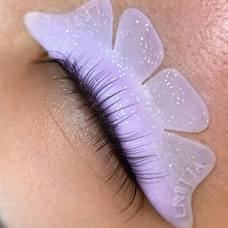 Purple lash extension gel being applied to a person's eyelash with 'LIMitta' branding.